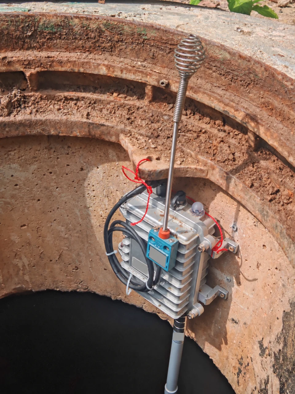 Spring-position sensor and monitoring station installed inside an underground chamber; equipment labels redacted