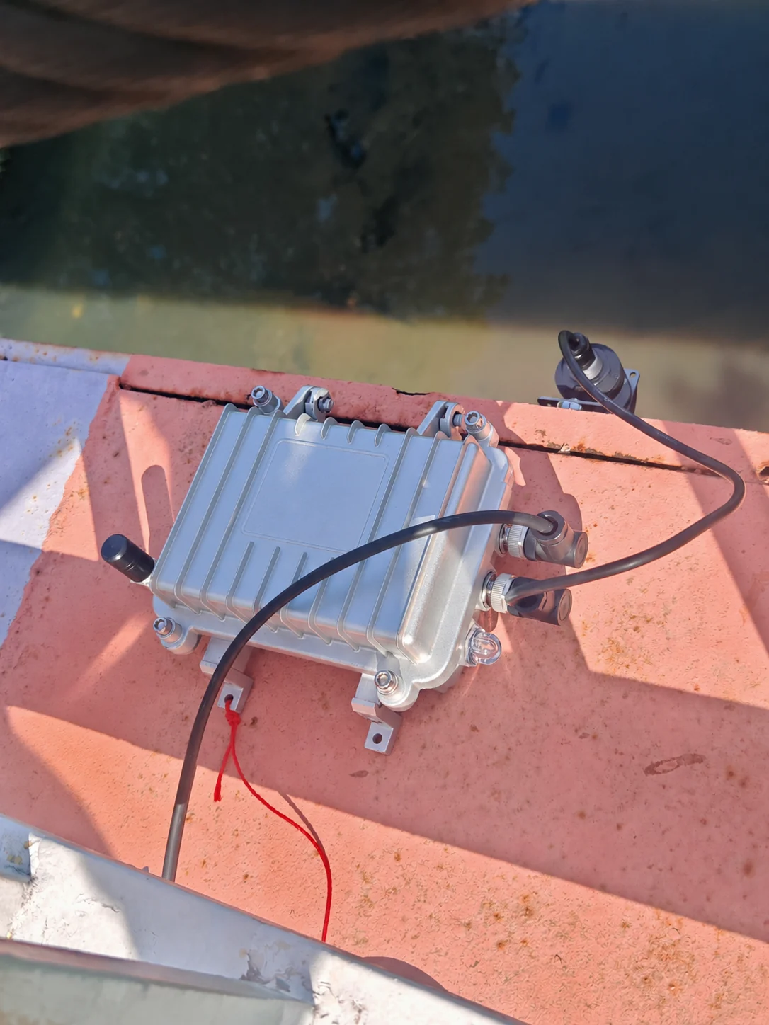 Monitoring hub, radar sensor and connected leads above a water channel; equipment label redacted